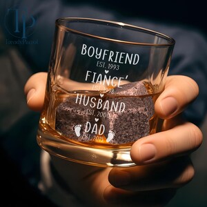 May include: A clear glass with the text "Boyfriend Est. 1993, Fiance' Est. 1998, Husband Est. 2000, Dad Est. 2015" and a small footprint symbol.