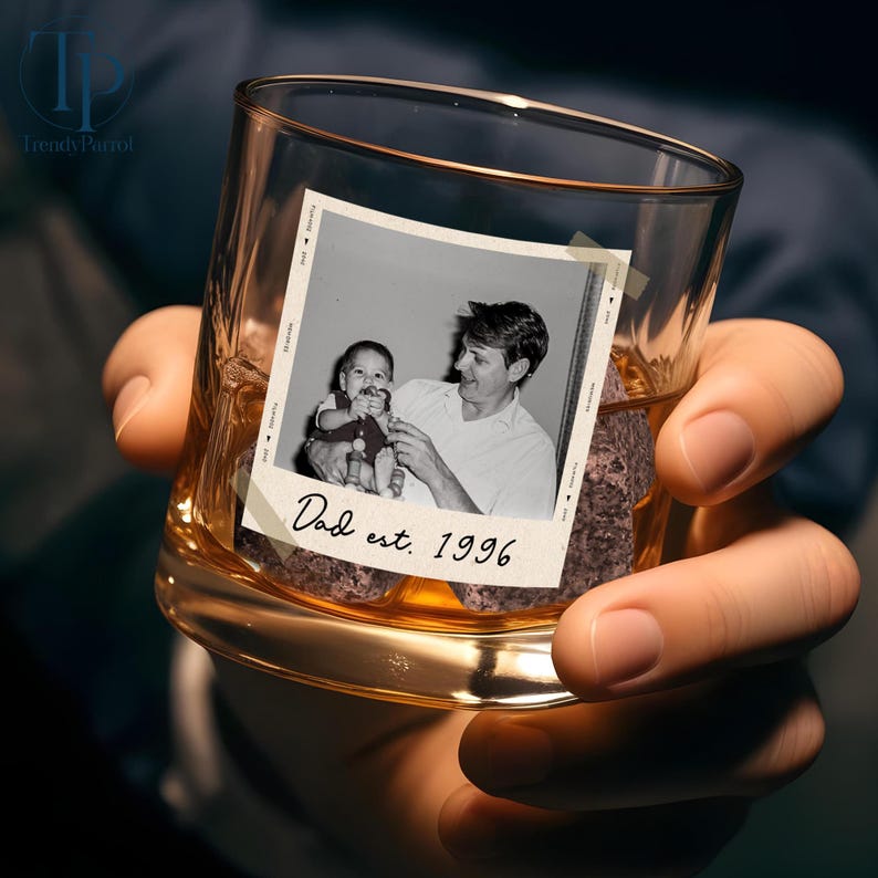 May include: A clear whiskey glass with a vintage photo of a father and child, with the text "Dad est. 1996". The glass is filled with a dark liquid and ice.