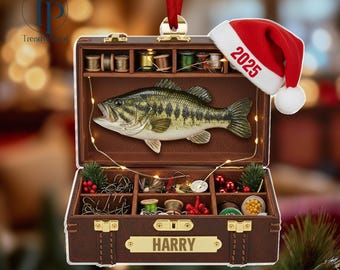 May include: A brown, open tackle box Christmas ornament with a large-mouth bass, fishing supplies, and a Santa hat with "2025" on it. The ornament has a red ribbon for hanging and the name "HARRY" on the front.