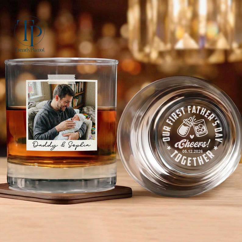 May include: A personalized whiskey glass with a photo of a father and baby, with the text "Daddy & Sophia." The glass also features a lid with the inscription "Our First Father's Day Together" and the date 05.12.2026.