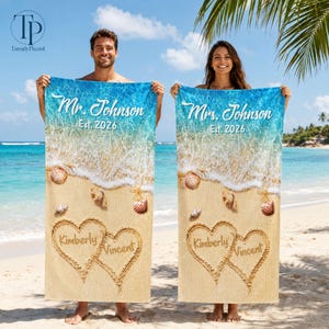 May include: Two rectangular beach towels featuring a printed sandy beach scene with ocean waves, seashells, and starfish. Each towel displays the text Mr. Johnson or Mrs. Johnson, Est. 2026, and two interlocking hearts drawn in the sand with the names Kimberly and Vincent.