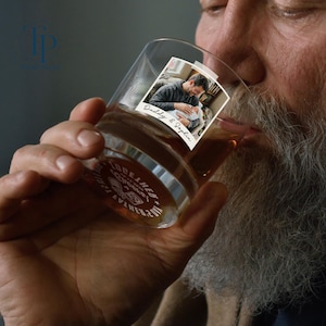 May include: A clear whiskey glass with a photo of a man holding a baby, labeled "Daddy & Sophia." The glass has a silver band with the words "TOGETHER" and "EST. 2017." The glass is filled with amber liquid.