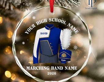 May include: A circular glass Christmas ornament featuring a blue and white marching band uniform with the name DAVID, a white plume, and a matching hat labeled FLUTE. The text reads YOUR HIGH SCHOOL NAME, MARCHING BAND NAME, and 2026.