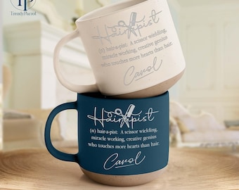 May include: Two ceramic mugs, one cream and one navy blue, stacked on a wooden tray. Each mug features the word "Hairapist" with a scissor graphic, a definition, and the name "Carol". The mugs have a two-tone design with a tan base.