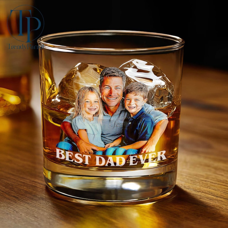 May include: A clear glass tumbler with a photo of a man and two children, filled with amber liquid and ice cubes. The words "BEST DAD EVER" are printed on the glass.