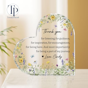 May include: A heart-shaped clear acrylic plaque with floral and butterfly accents. The plaque has the text "Thank you" and a personalized message. The TrendyParrot logo is in the upper left corner.