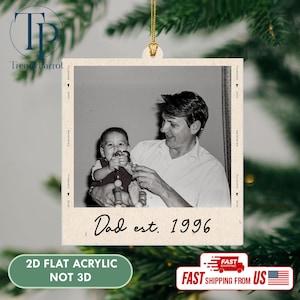 May include: A black and white acrylic ornament featuring a vintage photo of a father and child. The text "Dad est. 1996" is printed below the photo. The ornament is labeled "2D FLAT ACRYLIC NOT 3D".