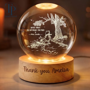 May include: A lit crystal ball night light on a wooden base. The etched design inside shows Winnie the Pooh and Piglet under a tree, with the text "Never forget the difference you make." The base reads "Thank you, Amelia."