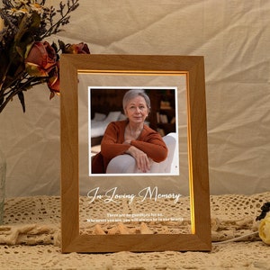 Könnte beinhalten: Ein Holzbildrahmen mit einem beleuchteten Foto einer Frau im Inneren. Der Rahmen trägt den Text "In Loving Memory" und das Zitat "There are no words that for us. Whenever you are, you will always be in our hearts."