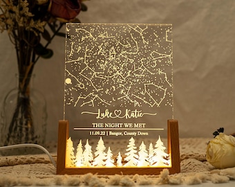Op de afbeelding: Een gepersonaliseerd sterrenkaart nachtlampje met een houten voet. Het licht toont een sterrenbeeldkaart met de namen "Luke & Katie" en de tekst "The Night We Met 11.09.22 | Bangor, County Down".