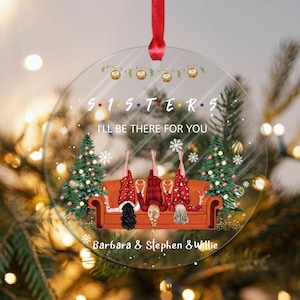 Puede incluir: Un adorno navideño redondo transparente con temática de Friends. Presenta tres figuras de dibujos animados sentadas en un sofá con un árbol de Navidad detrás. El texto "S.I.S.T.E.R.S. I'll be there for you" está impreso en el adorno. Los nombres "Barbara, Stephen & Willie" están impresos en la parte inferior.