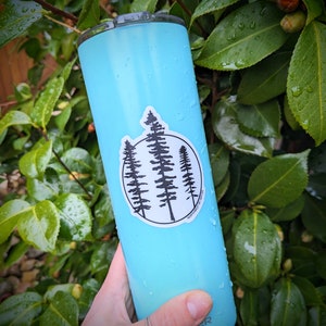 May include: A light blue reusable water bottle with a sticker of three black trees in a circle with the text "NORTHWEST FOREST" on the sticker.