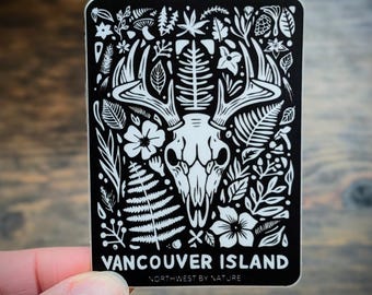 May include: Black and white sticker with a deer skull surrounded by floral and foliage designs. The text "Vancouver Island" and "Northwest by Nature" is at the bottom of the sticker.