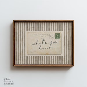 Op de afbeelding: Ingelijste wandkunst met een vintage ansichtkaartontwerp. De ansichtkaart leest "what's for dinner" in cursief schrift. De achtergrond heeft verticale grijze en witte strepen en de lijst is warmbruin.
