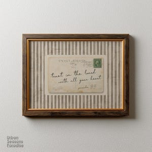 May include: Framed vintage postcard art print. The postcard features the text "trust in the lord with all your heart" and a green postage stamp. The frame is brown with a gold inner edge, set against a striped background.