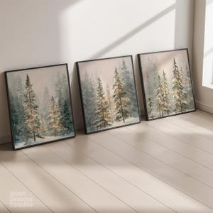 Puede incluir: Tres impresiones art&iacute;sticas enmarcadas que representan una pintura a la acuarela de una escena de bosque nevado con altos &aacute;rboles de hoja perenne. La obra de arte tiene una paleta de colores suaves, con tonos de verde, gris y beige. Los marcos son negros.