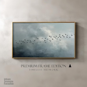 May include: A framed art print featuring a flock of birds in silhouette against a cloudy, muted blue and gray sky. The artwork is in a gold frame. Text at the bottom reads "PREMIUM FRAME EDITION" and "TIMELESS ARTWORK".