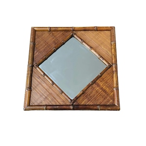 May include: A square wall mirror featuring a brown bamboo frame and a diamond-shaped central glass pane. The surrounding border is constructed from textured, thin bamboo slats arranged in a diagonal pattern, enclosed by a thick bamboo border.