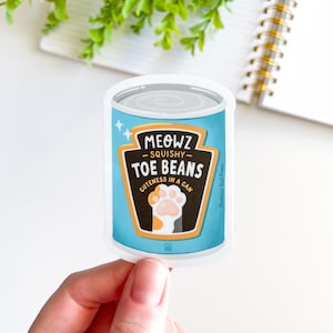 May include: A blue and white sticker with a cartoon can of cat food. The can says "MEOWZ SQUISHY TOE BEANS CUTENESS IN A CAN". There is a cartoon paw print on the can.