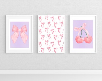 May include: Three framed prints with a pastel purple background. The left print features a large pink bow. The center print has a repeating pattern of pink bows on a white background. The right print features two pink cherries with a pink ribbon tied around the stems.