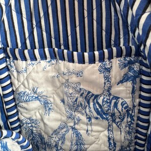 Peut inclure: Int&eacute;rieur d'un sac fourre-tout matelass&eacute;. Le sac pr&eacute;sente un ext&eacute;rieur &agrave; rayures bleues et blanches et un int&eacute;rieur blanc avec un imprim&eacute; tigre bleu. La doublure du sac est matelass&eacute;e, ajoutant une apparence textur&eacute;e.