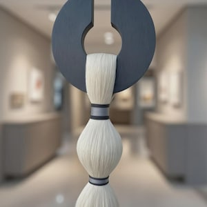 May include: Abstract sculpture featuring a dark gray, semi-circular shape with a central opening, holding a cascade of white fibers. The fibers are bound with gray and black bands, creating a unique, artistic display.