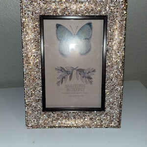 May include: A gold picture frame with a sparkly finish, featuring a butterfly illustration and the text "BEAUTIFUL BUTTERFLY. A butterfly fluttering on a colourful wings, fly to my side."