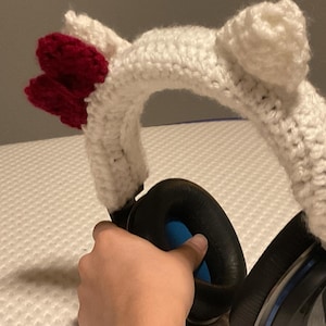 May include: White crocheted headband with red crocheted ears, designed to fit over headphones.