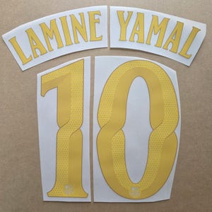 May include: A set of yellow heat transfer vinyl decals featuring the name LAMINE YAMAL in a curved font and the number 10 with a textured line pattern. Each digit includes a small FC Barcelona crest at the base on a white backing sheet.