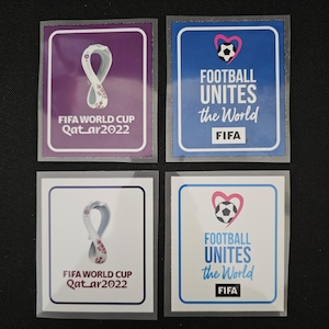 May include: Four square stickers with different designs. The top left sticker is purple with a white and gold trophy design and the text "FIFA WORLD CUP Qatar2022". The top right sticker is blue with a pink heart containing a white soccer ball and the text "FOOTBALL UNITES the World FIFA". The bottom left sticker is white with a white and gold trophy design and the text "FIFA WORLD CUP Qatar2022". The bottom right sticker is white with a pink heart containing a white soccer ball and the text "FOOTBALL UNITES the World FIFA".