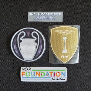 Peut inclure: Trois écussons brodés : un écusson circulaire du trophée de l'UEFA Champions League, un écusson doré en forme de bouclier FIFA Intercontinental Champions 2025 et un écusson rectangulaire UEFA Foundation for Children avec une étiquette Final Budapest 2026.