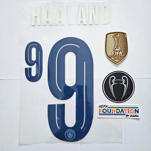 May include: A set of iron-on patches for a soccer jersey. The patches include the number 9, the name "HAALAND", a FIFA World Cup Champion patch, a UEFA Champions League patch, and a UEFA Foundation for Children patch.