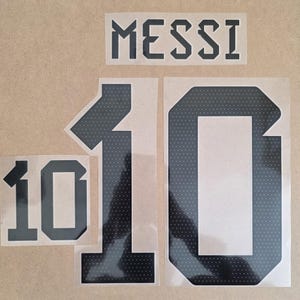 May include: A set of black heat transfer decals featuring the name MESSI in a bold, angular font, along with three separate number 10 designs. The numbers feature a dark, perforated texture pattern, while the name is solid black lettering.
