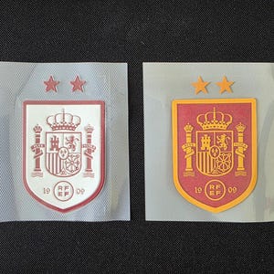 May include: Two rectangular patches featuring the Royal Spanish Football Federation crest. One patch is white with red details and two red stars, while the other is red with yellow details and two yellow stars. Both include the text 19 RF EF 09.