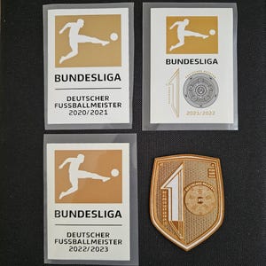 May include: Four gold and white stickers with the Bundesliga logo and the text "Deutscher Fussballmeister" and the years 2020/2021, 2021/2022, and 2022/2023.