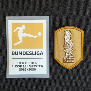 Könnte beinhalten: Ein rechteckiger Bundesliga-Aufkleber mit einer goldenen Fußballer-Silhouette und dem Text "DEUTSCHER FUSSBALLMEISTER 2025/2026" neben einem goldenen schildförmigen Aufnäher, der einen Vogel mit Fußball und den Text "35 DEUTSCHER MEISTER" zeigt.