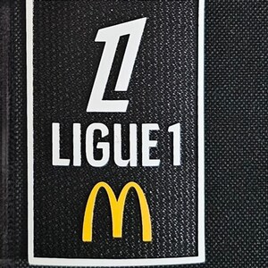 May include: A black and white patch with the text "Ligue 1" and a white number "1" above the text. A yellow McDonald's "M" logo is below the text.