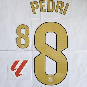 Op de afbeelding: Een set strijklabels voor een voetbaltenue. De labels zijn goud en zwart en bevatten het nummer 8 en de naam "PEDRI".
