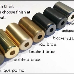 K&ouml;nnte beinhalten: Eine Finish-Chart zeigt zylindrische Metallobjekte in verschiedenen Ausf&uuml;hrungen, darunter antike Patina, poliertes Messing, geb&uuml;rstetes Messing, Rohmessing, geschw&auml;rztes Messing, Antikschwarz und poliertes Chrom. Text weist auf die Finish-Optionen hin.