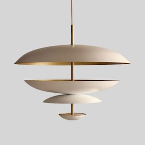 May include: A contemporary pendant light with a layered design. It features off-white, saucer-shaped shades with gold-coloured interiors, suspended from a central rod. The minimalist design is suitable for modern interiors. The light is suspended from the ceiling.