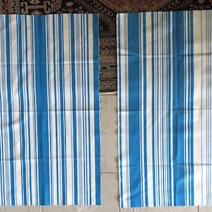 Può includere: Due pezzi di tessuto a righe blu e bianche. Il tessuto ha una trama tessuta ed è fatto di cotone.