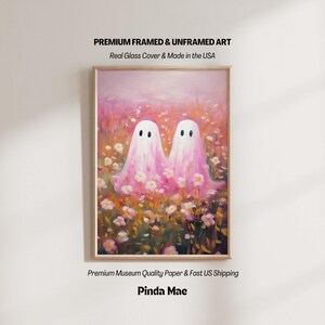 May include: A framed art print featuring two white ghost figures standing in a field of pink and orange flowers. The text at the top reads PREMIUM FRAMED & UNFRAMED ART, Real Glass Cover & Made in the USA. The bottom text reads Pinda Mae.