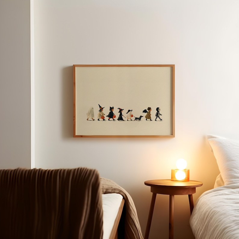 May include: A framed horizontal wall art print featuring a line of eight children in various Halloween costumes, including a ghost, witches, and a skeleton, walking in a row with a small black dog on a light cream-colored background.