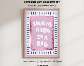 Puede incluir: Impresión artística enmarcada con el texto "SNUG AS A BUG IN A RUG" en blanco sobre un fondo lila claro. El marco es de madera clara, con detalles en azul y rosa. El texto "Pinda Mae" está en la parte inferior.