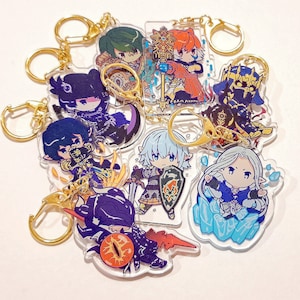Könnte beinhalten: Ein Set aus acht bunten Charakter-Schlüsselanhängern mit goldenen Schlüsselringen. Die Charaktere sind im Anime-Stil gehalten und beinhalten einen blauhaarigen Charakter mit einem Schwert, einen lilahaarigen Charakter mit einem Stab, einen grünhaarigen Charakter mit einer Krone und einen rothaarigen Charakter mit einem Stab.