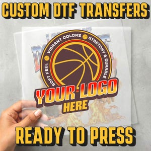 May include: A custom DTF transfer sheet featuring a circular graphic with a basketball illustration and the text VIBRANT COLORS, STRETCHY & DURABLE, SOFT FEEL, and YOUR LOGO HERE. The top text reads CUSTOM DTF TRANSFERS and the bottom reads READY TO PRESS.