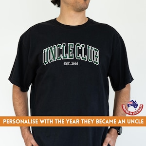 May include: Black t-shirt with white text that reads "Uncle Club Est. 2016" in a green and white arch design.