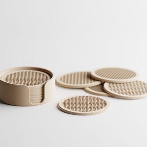 May include: A collection of beige coasters with a woven design, presented with a coordinating holder. The coasters are circular, with a diameter of about 10 cm. The holder is cylindrical, designed for tidy storage of the coasters.