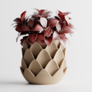 Könnte beinhalten: Eine dekorative beige Vase mit einem einzigartigen, geschichteten Design, die lebendige rote und burgunderfarbene Blätter enthält. Die Vase hat eine strukturierte Oberfläche und einen abgerundeten Boden, was einen modernen, künstlerischen Look erzeugt.
