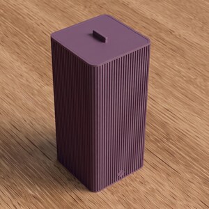 Peut inclure: Un grand récipient de stockage rectangulaire de couleur violet foncé, doté d'une texture nervurée verticale sur les quatre côtés. Le récipient comporte un couvercle plat assorti avec une petite poignée rectangulaire centrée et un logo discret.